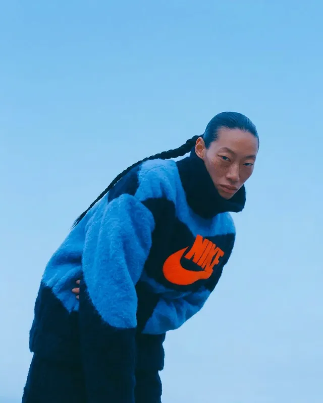 Woman in a vibrant oversized sweater against a blue sky.