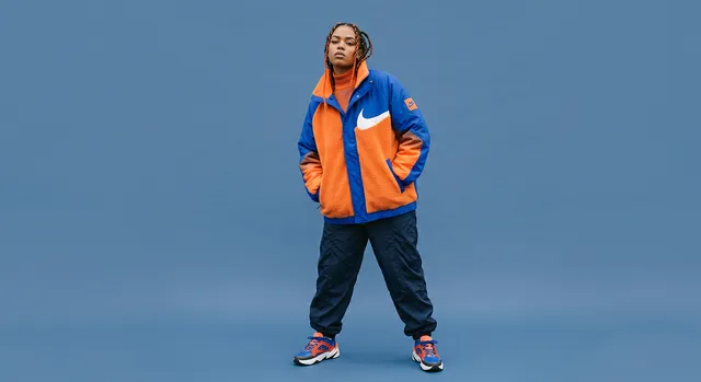 Woman standing in a vibrant outfit against a blue background.
