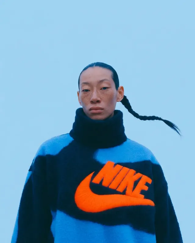 Portrait of a woman wearing a blue and black patterned sweater with the Nike logo.