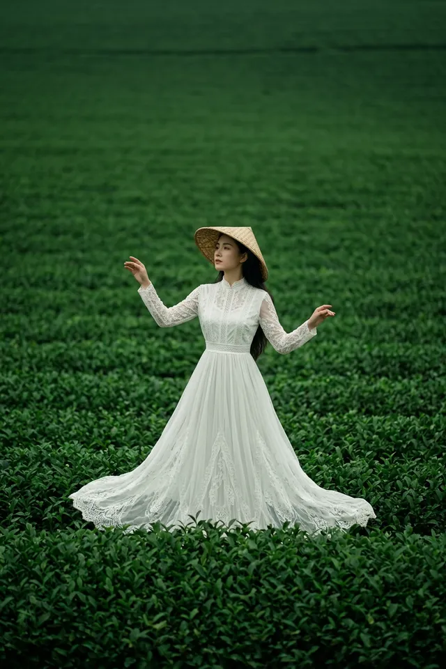 A woman in a white dress stands in green tea fields under soft natural lighting.
