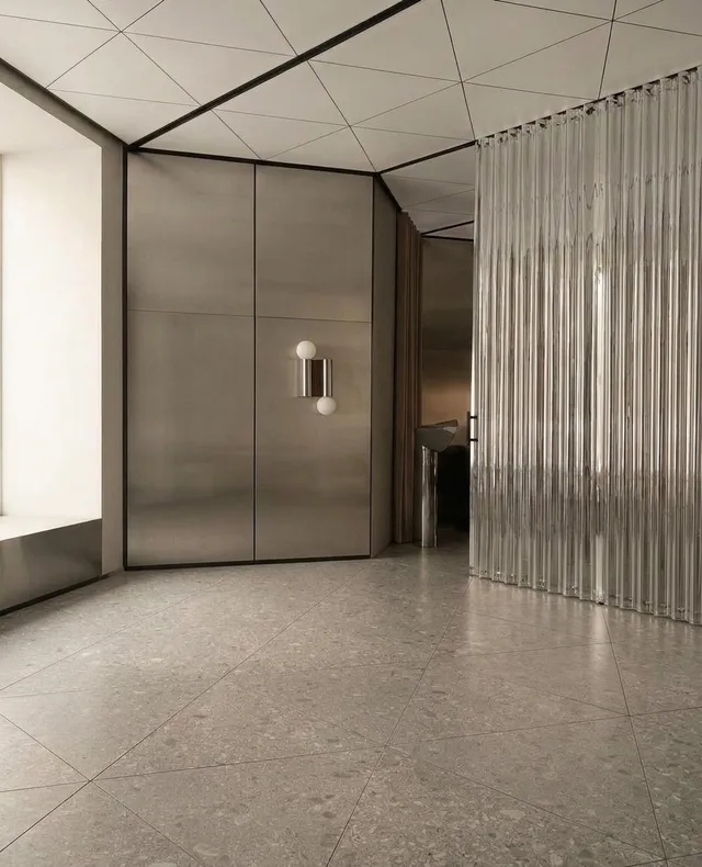 A modern interior space showcasing sleek, metallic surfaces and geometric designs. The mood is serene with a minimalistic style dominated by neutral colors and reflective textures.