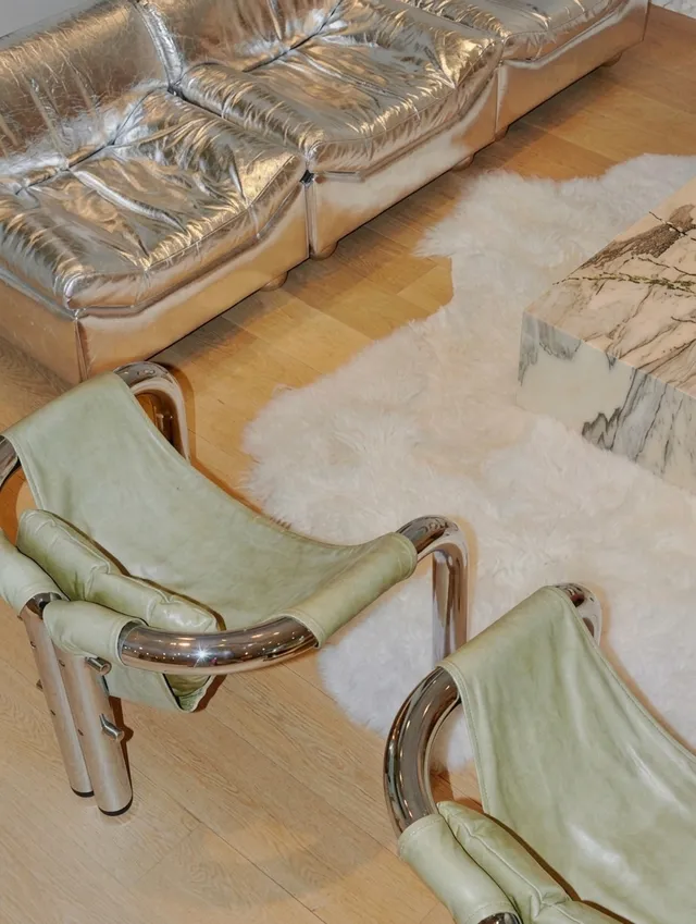 A stylish interior featuring metallic furniture and a plush fur rug, captured in a crisp photograph. The dominant colors are silver and soft green, creating a modern and luxurious atmosphere.
