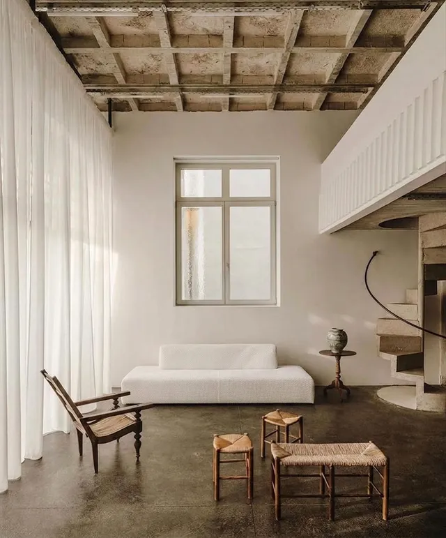 A serene interior scene showcasing minimalistic furniture and natural light. The color palette features soft neutrals with a touch of earthy tones.